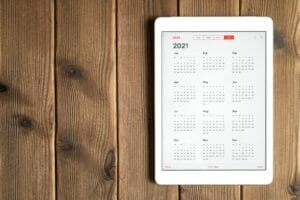 a tablet with an open calendar for 2021 year on a wooden boards table background. space for text.