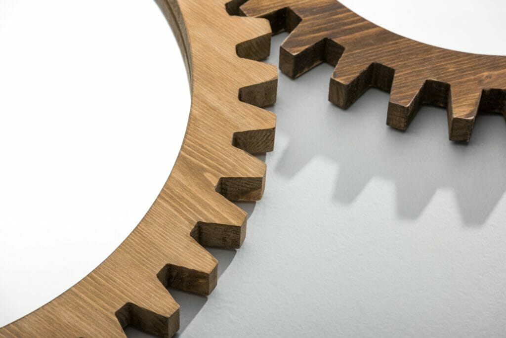 Close-up cropped view of mirrors framed by wooden cogwheels lying on white