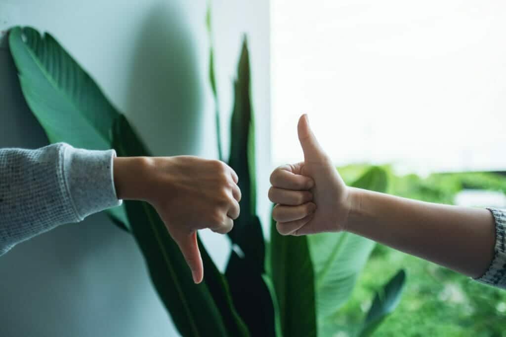 Closeup image of two people making thumbs up and thumbs down hands sign