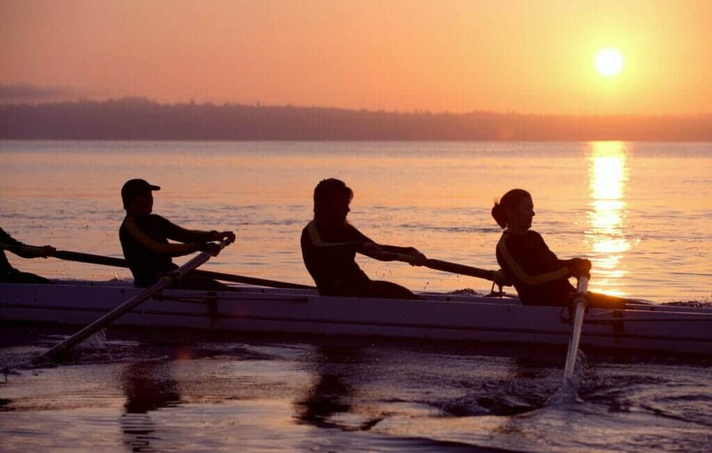 Four people rowing at sunset