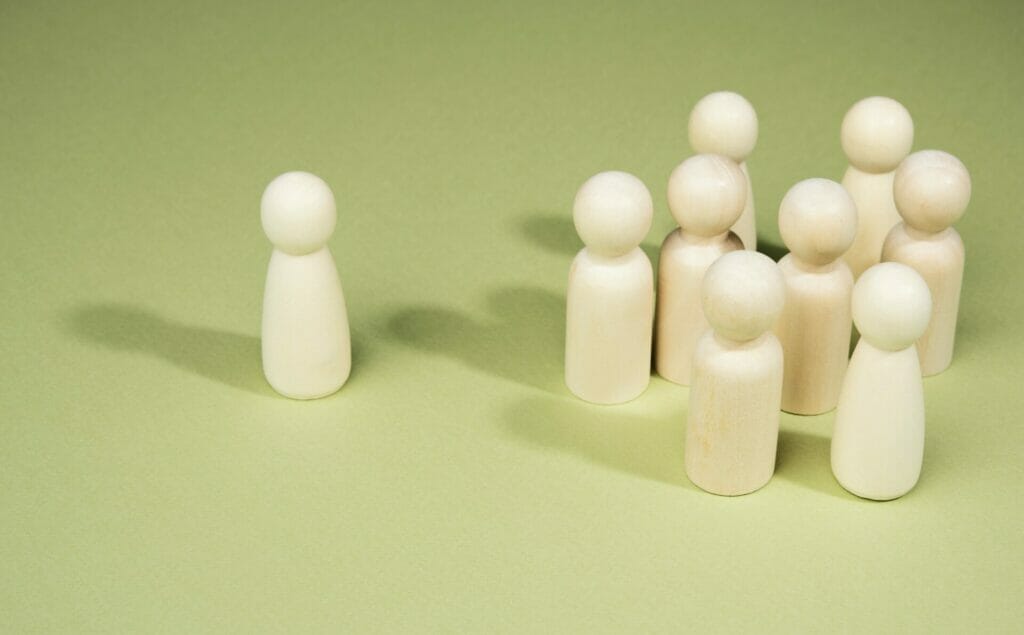 Wooden men stand in a group near one on a green background