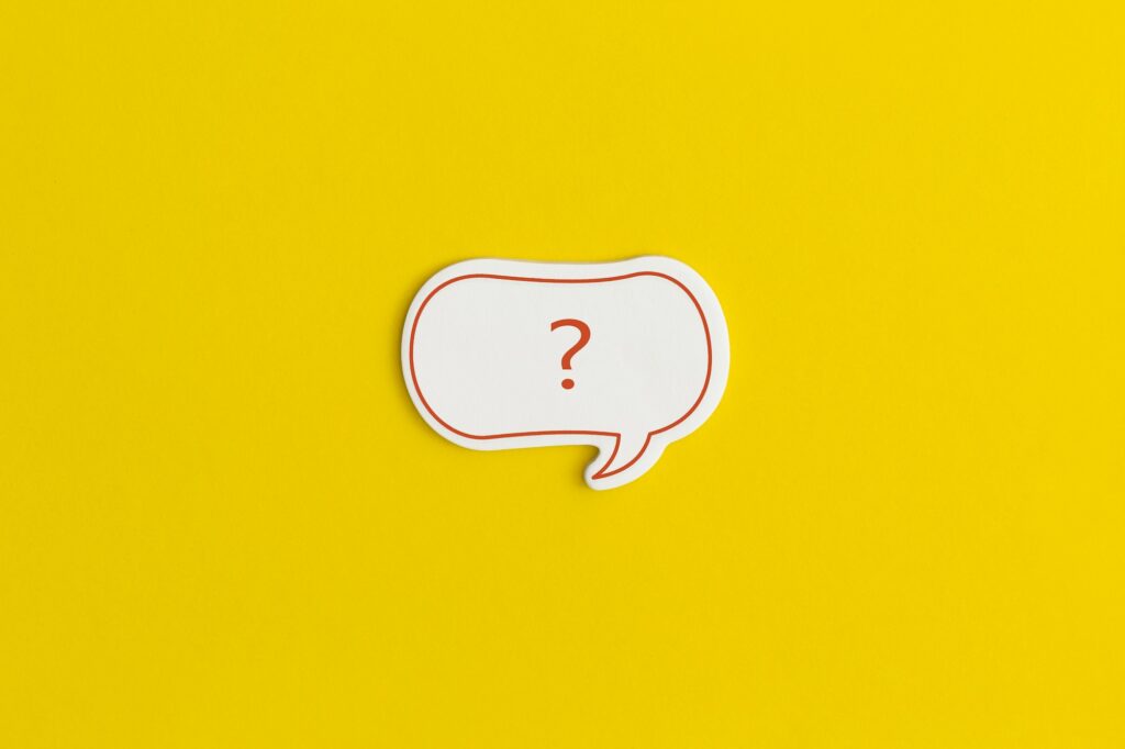 Paper speech bubble on a yellow background. Question mark.