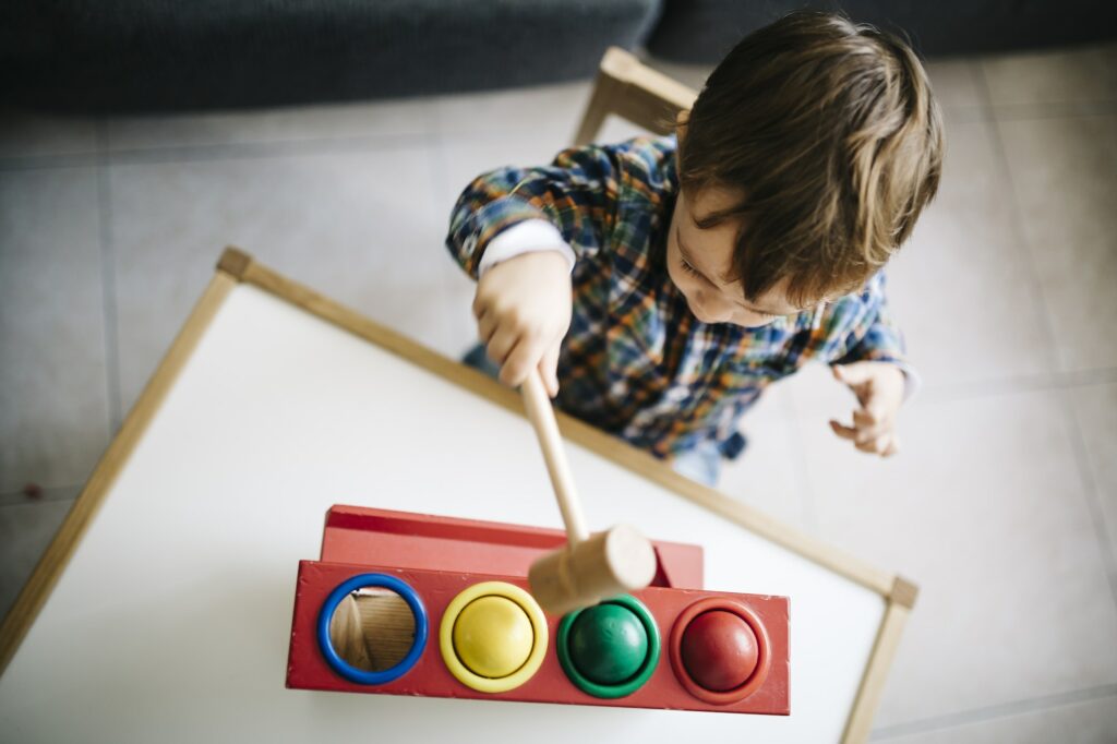 Little boy playing with wooden motor skill toy