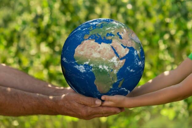 Senior man and child holding Earth planet. Elements of this image furnished by NASA