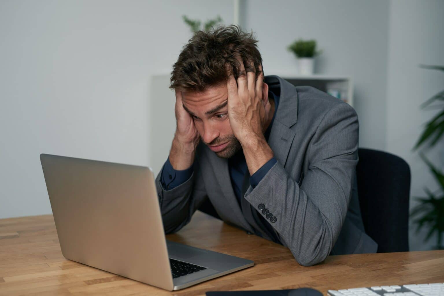 Portrait of an overwhelmed businessman sitting at his desk with his face in his hands