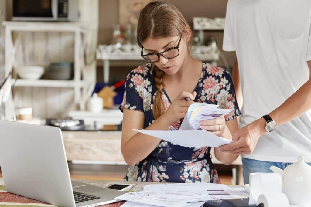 Concentrated female model wears spectacles, does paperwork, calculates numbers for making financial