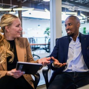 man in black suit jacket sitting beside woman in brown blazer